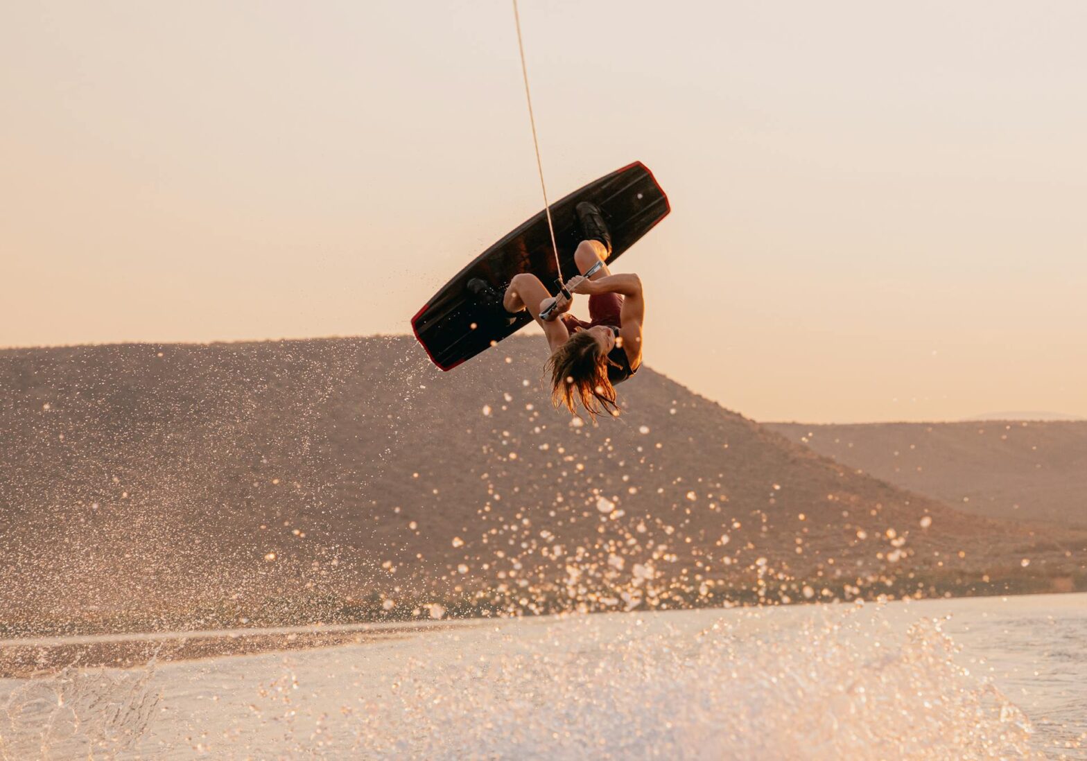 Man wake boarding behind luxury yacht